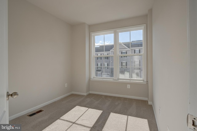 empty room with carpet flooring, visible vents, and baseboards