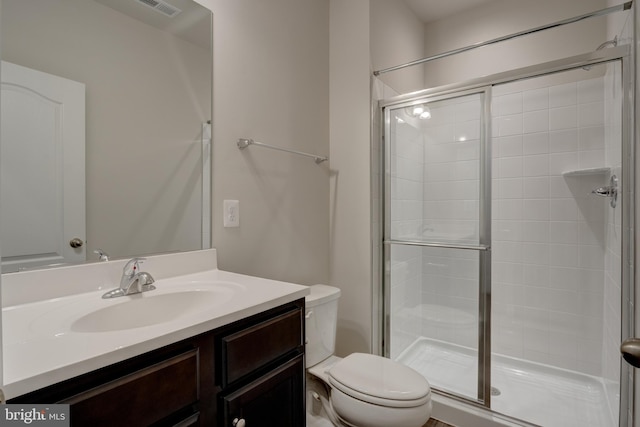 bathroom featuring vanity, a shower stall, and toilet