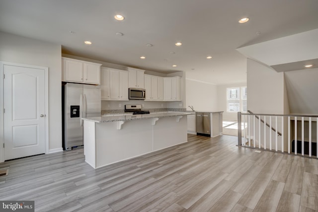 kitchen featuring light wood-style floors, appliances with stainless steel finishes, white cabinets, and a center island