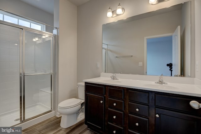 full bath with a sink, a shower stall, toilet, and wood finished floors