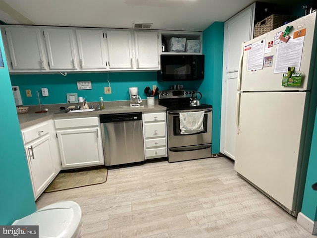 kitchen featuring open shelves, appliances with stainless steel finishes, light wood-style floors, white cabinets, and a sink