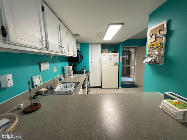 kitchen with visible vents, stove, freestanding refrigerator, white cabinets, and black microwave