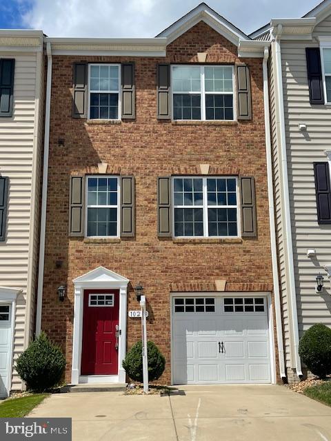 townhome / multi-family property featuring driveway and brick siding