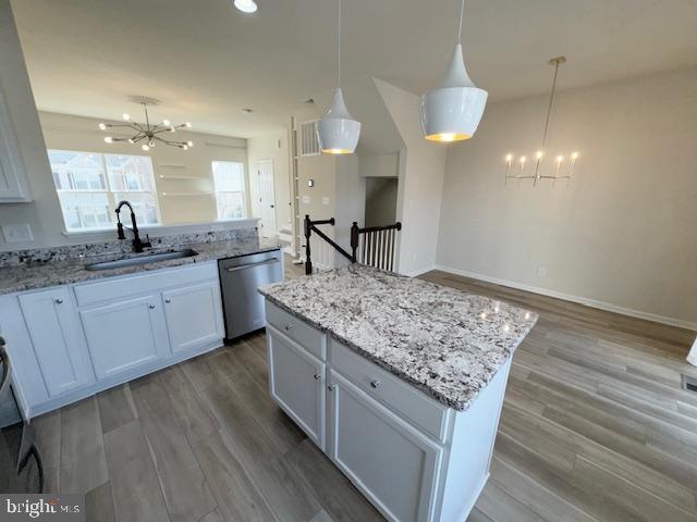 kitchen featuring a sink, a notable chandelier, stainless steel dishwasher, and wood finished floors