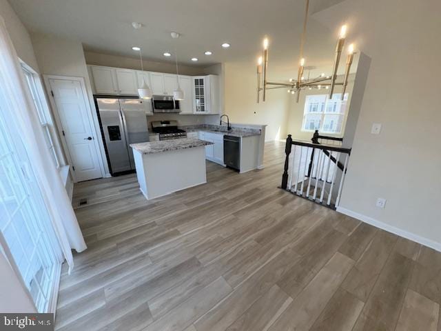 kitchen with recessed lighting, a kitchen island, white cabinets, appliances with stainless steel finishes, and light wood-type flooring