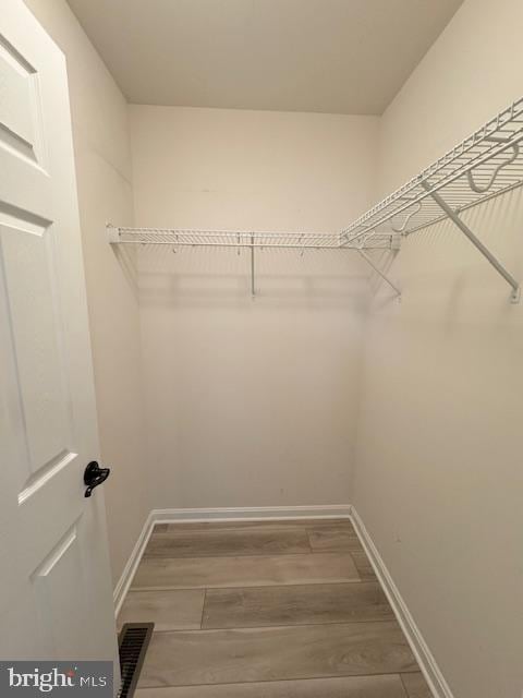 spacious closet featuring wood finished floors and visible vents