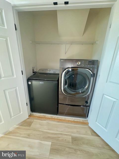 washroom featuring laundry area, independent washer and dryer, and light wood-style flooring