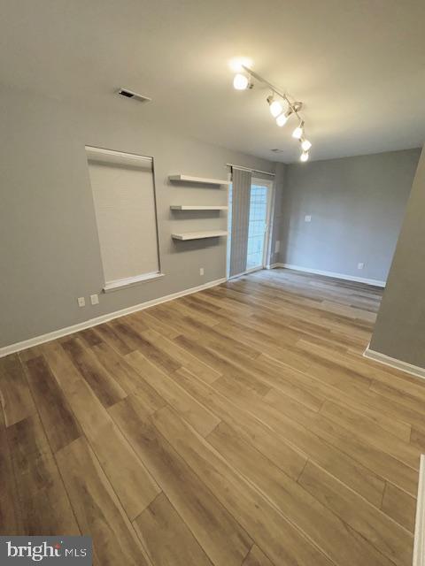 spare room featuring visible vents, baseboards, and wood finished floors
