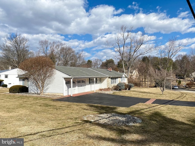 view of front of property with a garage, driveway, a front lawn, and a chimney