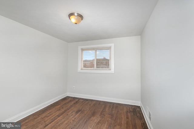 unfurnished room featuring visible vents, baseboards, and dark wood finished floors