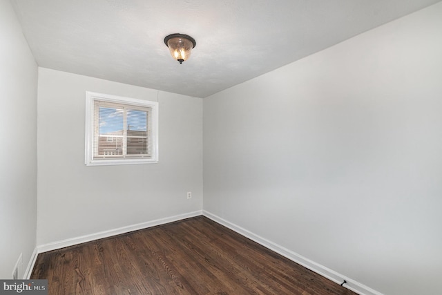 empty room with dark wood-style floors and baseboards