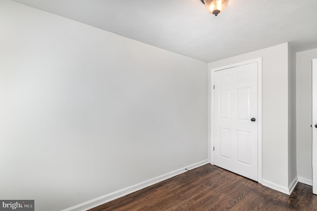 unfurnished bedroom with dark wood-type flooring and baseboards