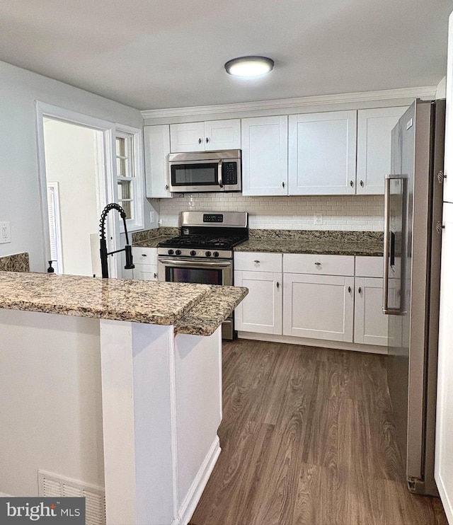 kitchen with stainless steel appliances, dark wood-type flooring, stone counters, and white cabinets