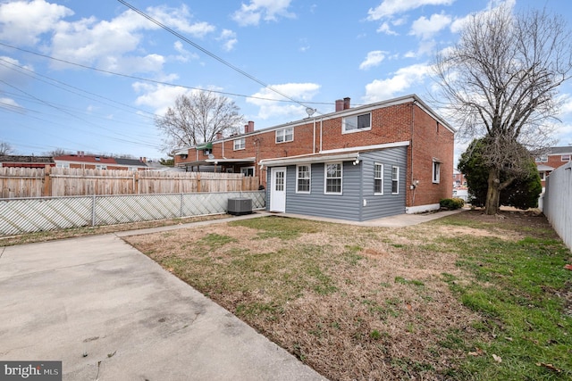 rear view of property featuring brick siding, a lawn, a patio area, cooling unit, and a fenced backyard