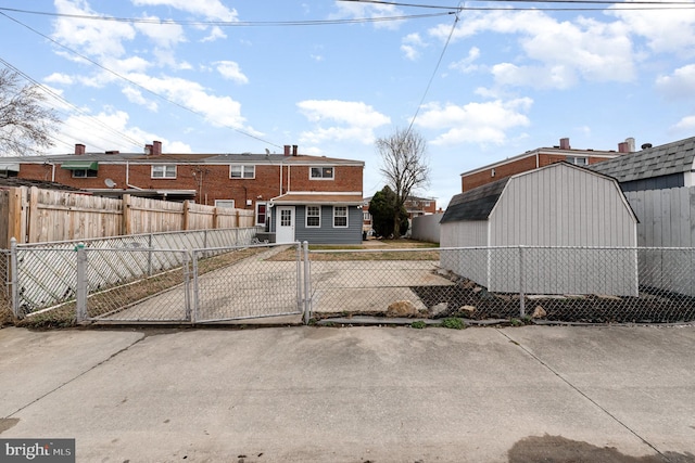 exterior space featuring a fenced front yard, a gate, a shed, and an outbuilding