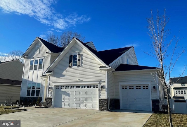 traditional home featuring an attached garage, stone siding, and driveway