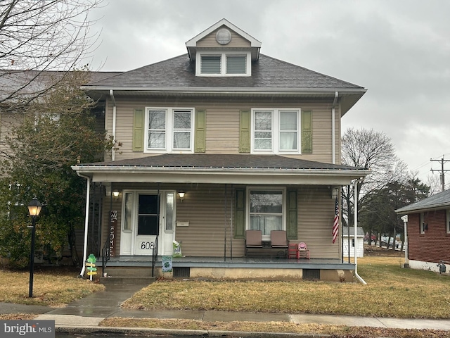 traditional style home featuring roof with shingles, a porch, and a front lawn