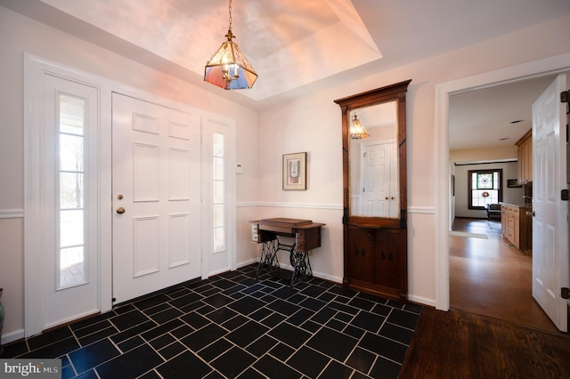 foyer entrance with a raised ceiling and baseboards