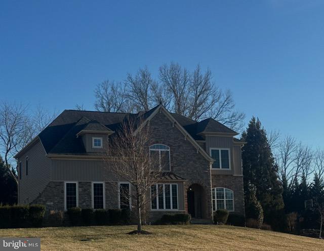 view of front of house featuring stone siding and a front lawn