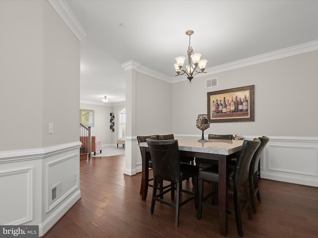 dining space featuring visible vents, a wainscoted wall, dark wood-style floors, an inviting chandelier, and crown molding