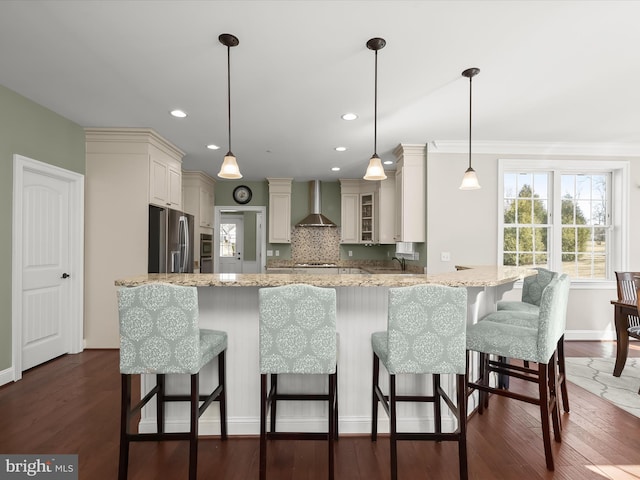 kitchen with backsplash, stainless steel fridge, wall chimney exhaust hood, and dark wood-style flooring