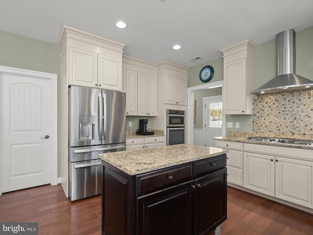 kitchen featuring visible vents, dark wood-style floors, appliances with stainless steel finishes, wall chimney range hood, and light stone countertops