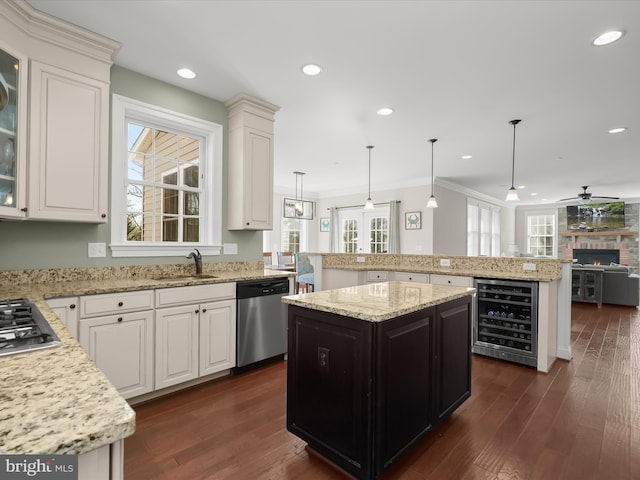 kitchen with beverage cooler, a sink, open floor plan, a center island, and stainless steel appliances