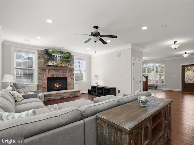 living room with visible vents, ornamental molding, a fireplace, baseboards, and dark wood-style flooring