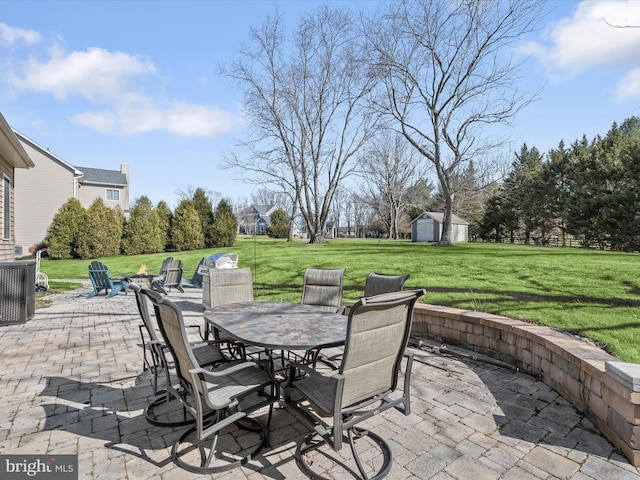 view of patio featuring outdoor dining space, an outbuilding, a storage unit, and central AC unit