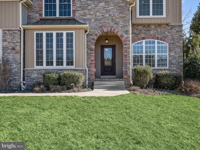 view of exterior entry with a lawn and board and batten siding