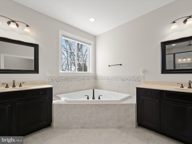 full bathroom featuring a garden tub, two vanities, and a sink