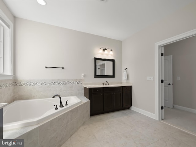 bathroom with baseboards, vanity, and a garden tub