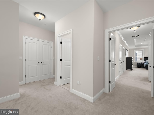 hall with crown molding, visible vents, baseboards, and light carpet