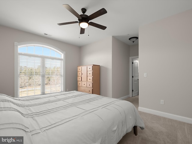 bedroom with visible vents, light colored carpet, baseboards, and ceiling fan