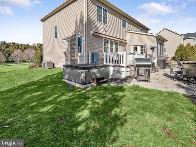 rear view of property featuring a patio, central air condition unit, a yard, and a hot tub