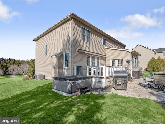 rear view of house with central AC unit, a patio, a hot tub, and a lawn