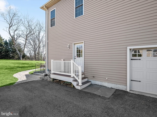 entrance to property featuring a yard and a garage