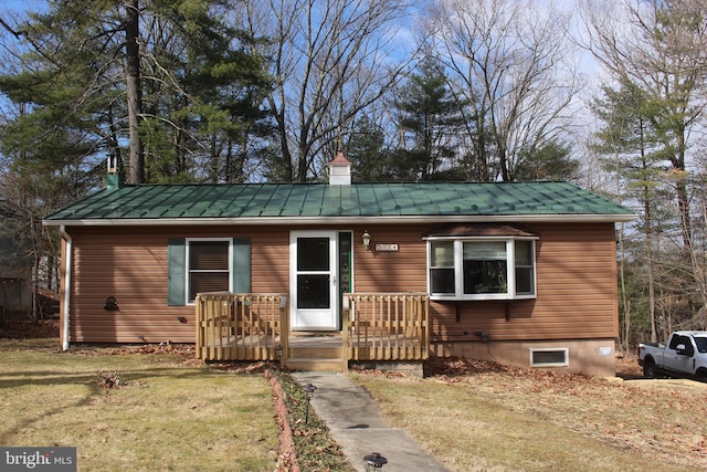 view of front facade with a chimney, metal roof, a standing seam roof, and a front yard