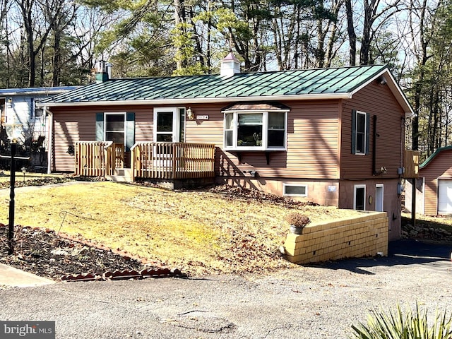 view of front of property featuring a standing seam roof, metal roof, and a chimney