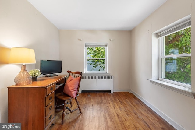 office area featuring radiator heating unit, plenty of natural light, hardwood / wood-style flooring, and baseboards