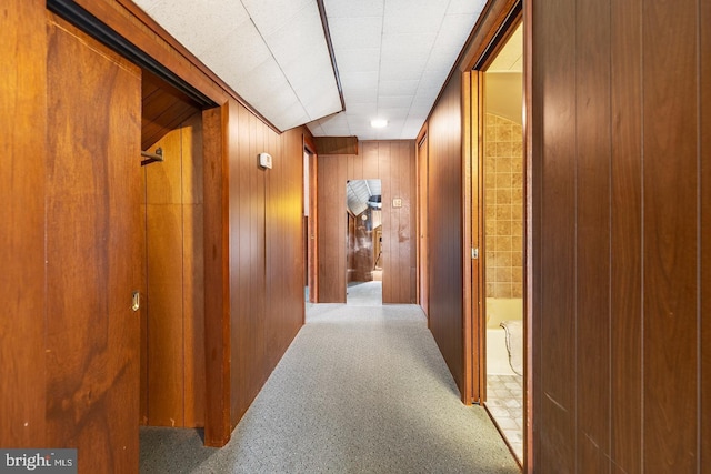 hall with wooden walls and carpet flooring