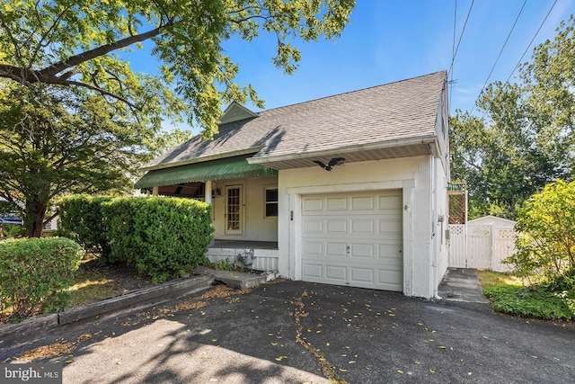 view of front of home featuring a garage, a shingled roof, fence, and aphalt driveway