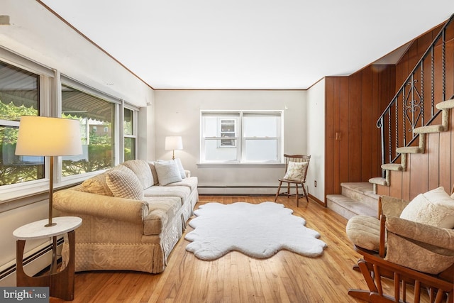 interior space with a baseboard heating unit, wood finished floors, stairs, and baseboards