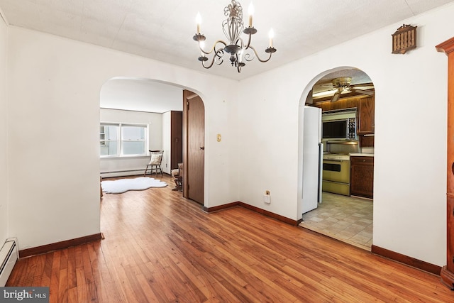 unfurnished dining area featuring a baseboard radiator, light wood-style flooring, arched walkways, and baseboards