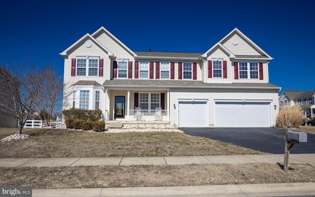 traditional-style house featuring a garage, covered porch, and driveway