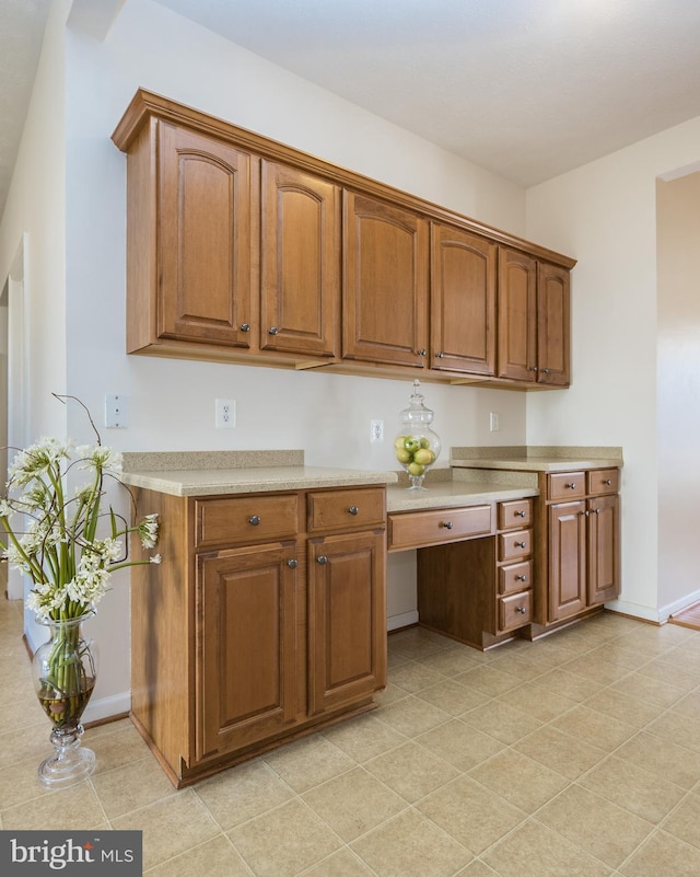 kitchen with light countertops, brown cabinetry, and baseboards