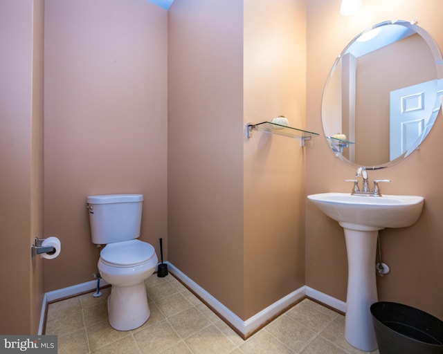 bathroom with toilet, tile patterned flooring, baseboards, and a sink