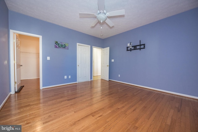 unfurnished bedroom with a textured ceiling, a closet, hardwood / wood-style flooring, and baseboards