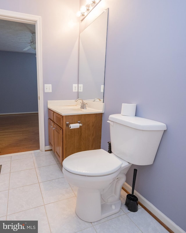 half bathroom featuring baseboards, vanity, toilet, and tile patterned floors