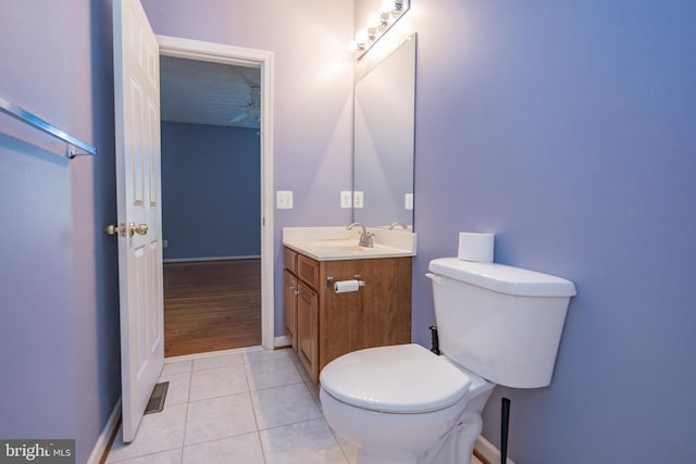 bathroom with tile patterned flooring, toilet, vanity, a ceiling fan, and baseboards